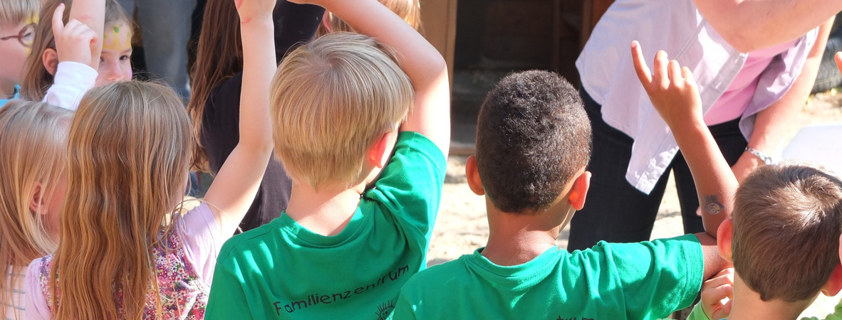 Sommerlich gekleidete Kindergruppe beteiligt sich per Handheben
