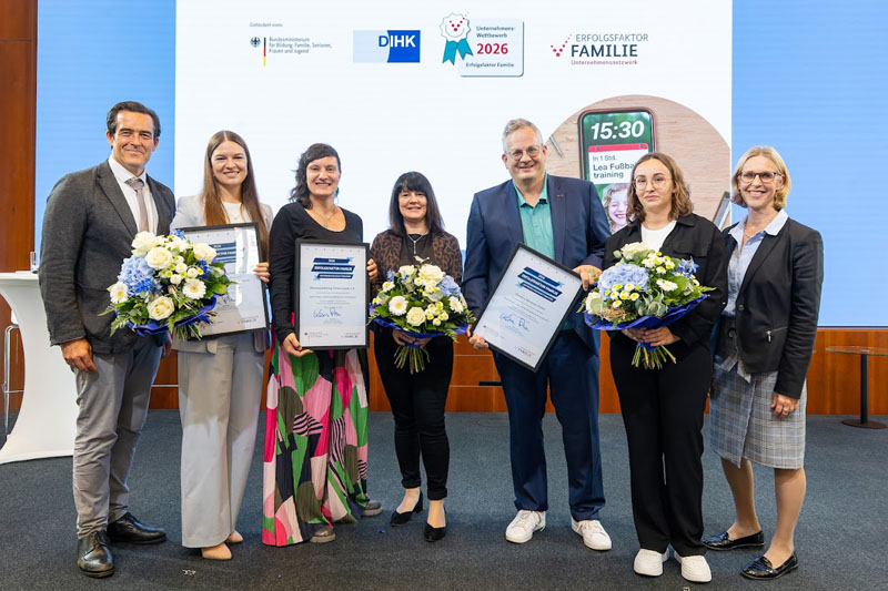 Eine Gruppe von Frauen und Männern hält Blumen und Urkunden in den Händen